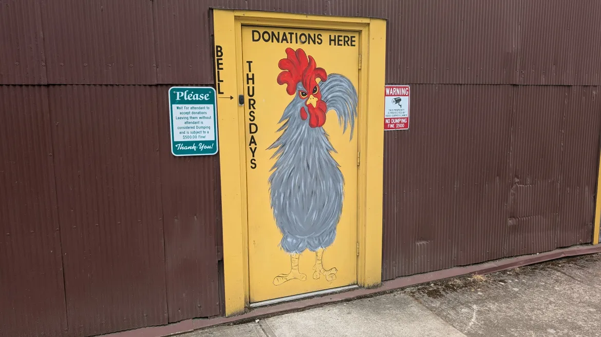 The thrift store donation drop-off door painted with a rooster and 'Donations Here — Thursdays'