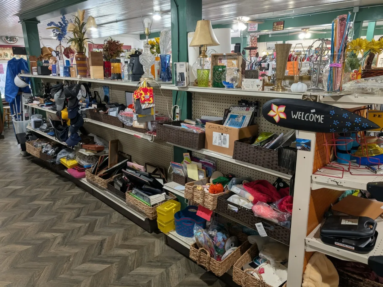 Inside the Rowdy Rooster Thrift Store — shelves full of housewares and a painted Welcome sign